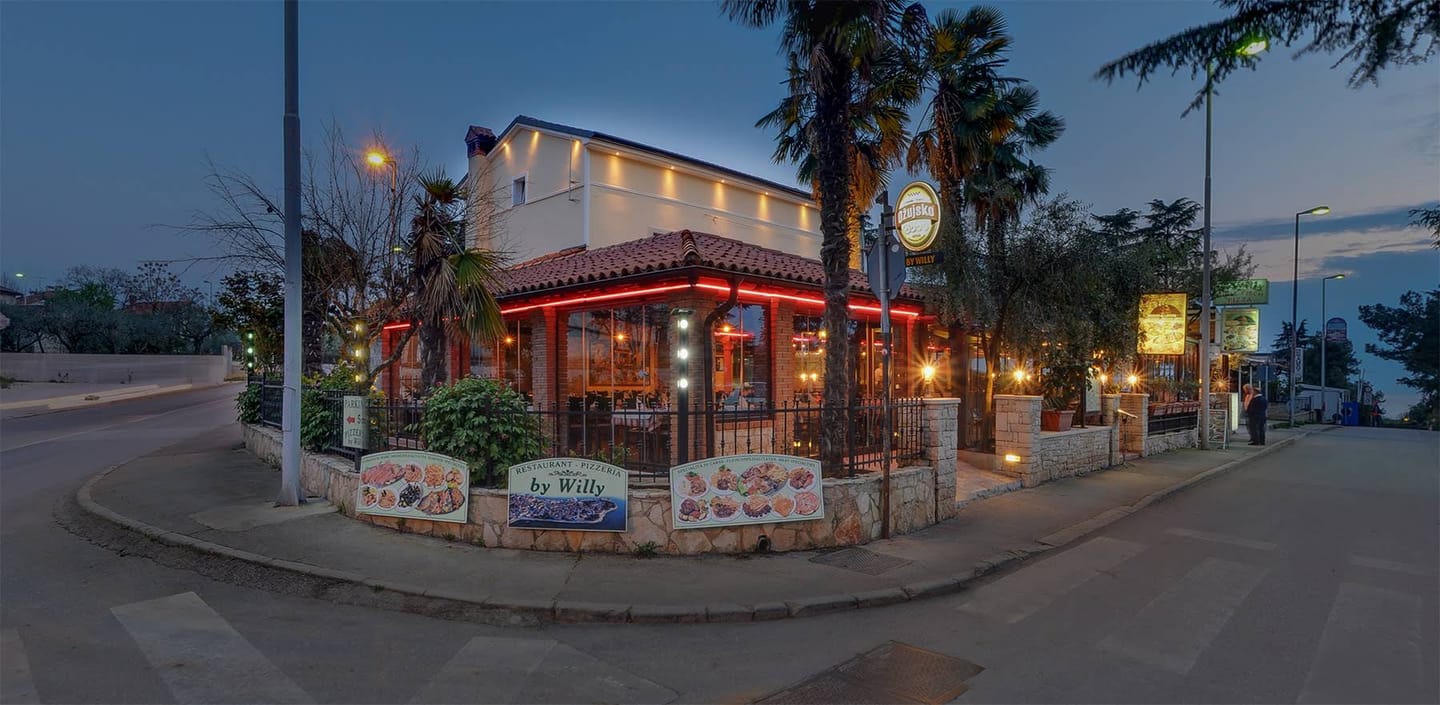 Terasa restorana Willy u suton — crveno neonsko svjetlo, palme i kamena ograda